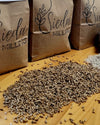 Brown paper bags labeled 'Sieda Milling' are arranged on a wooden table with loose rye grains and flour spilled in front.