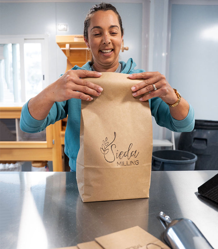 Opening a bag of stoneground flour in the kitchen, introducing beginners to baking with stoneground flour