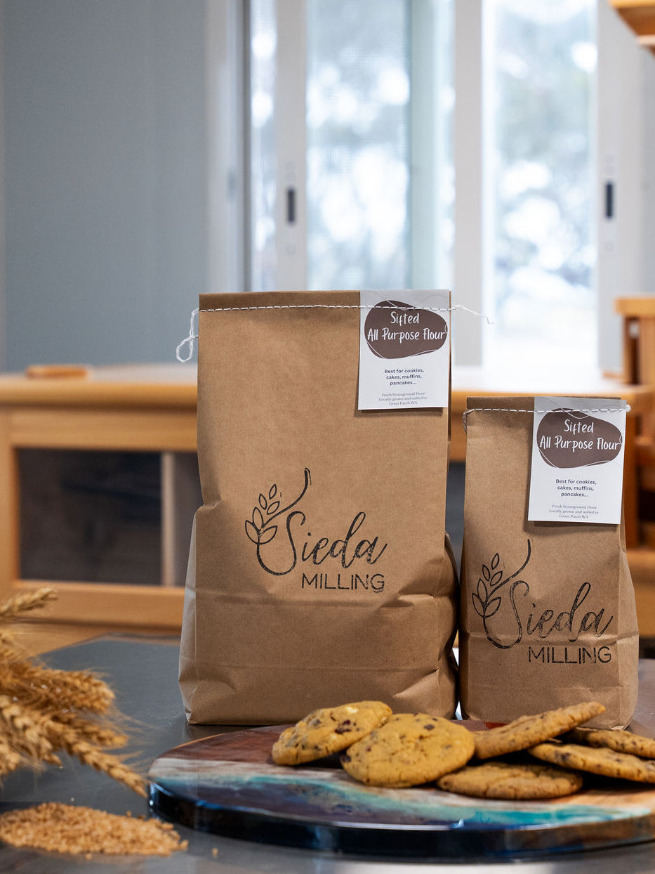 " bags of Stone-milled all purpose flour by Sieda Milling, shown with baked biscuits and everyday baking ingredients
