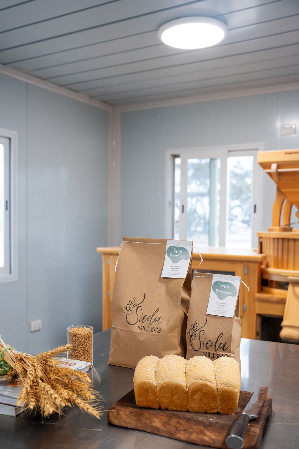 Two loaves of bread on a wooden cutting board made with High-protein bread flour which was stone-milled with Australian grown wheat and is ideal for sourdough and artisan bread baking