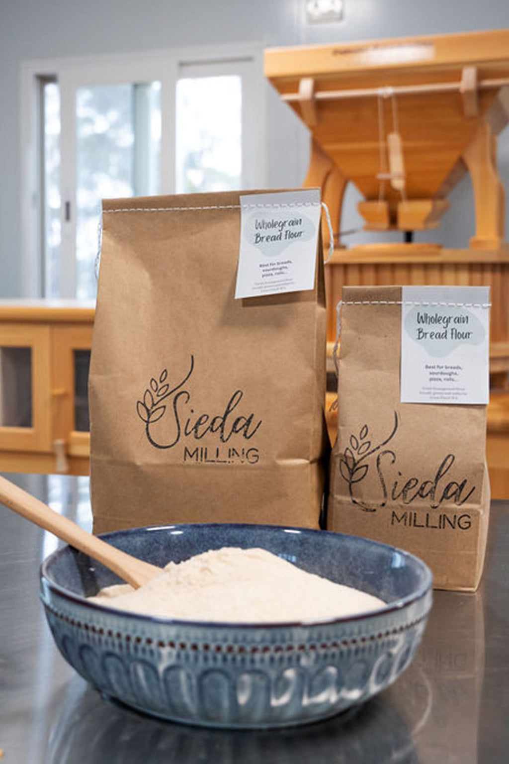 Two bags of Sieda Milling flour with a blue bowl filled with Wholegrain bread flour made from stone-milled wheat, ideal for sourdough and artisan bread baking